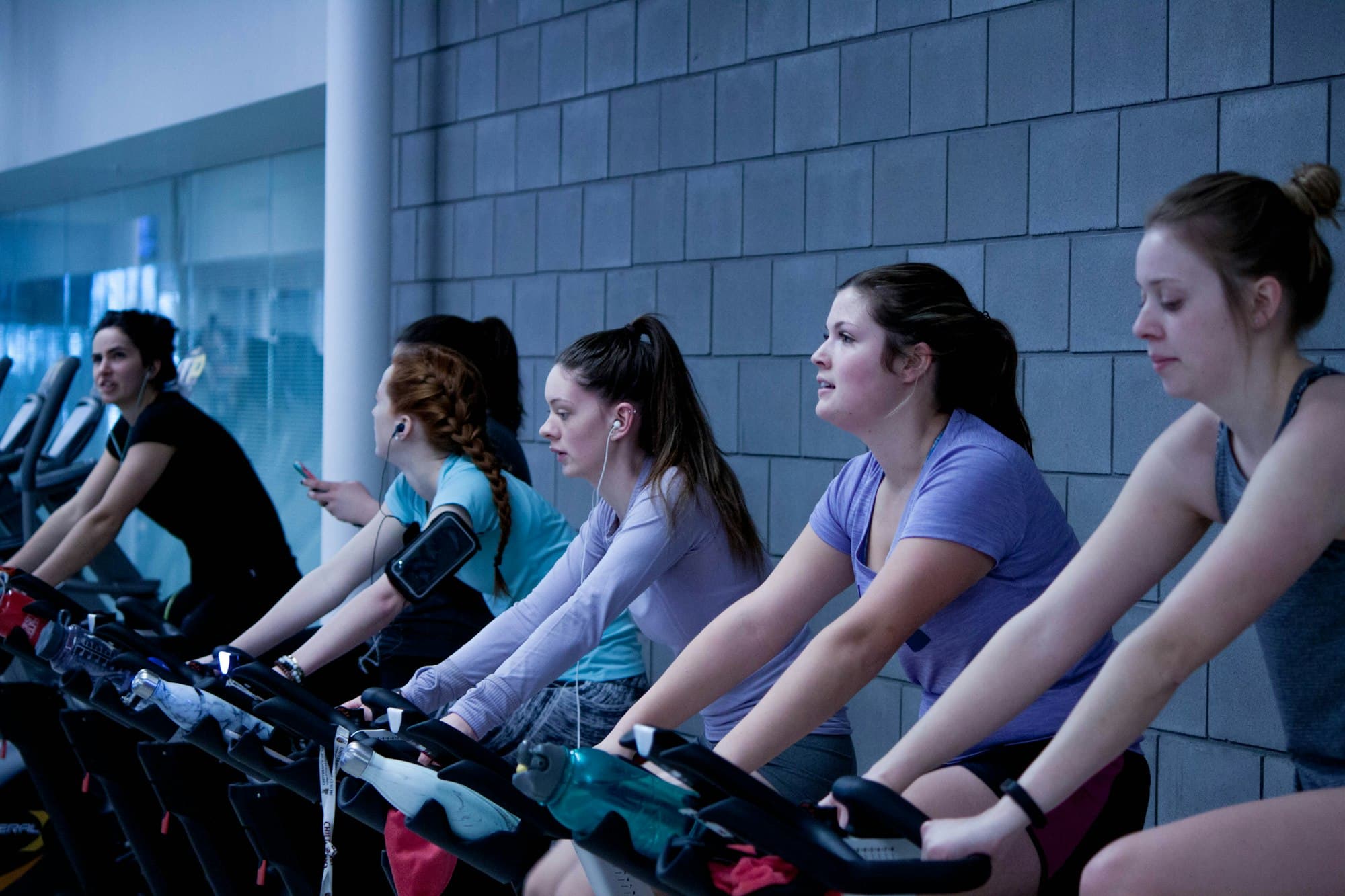 Riders on stationary bikes in an indoor cycling class.
