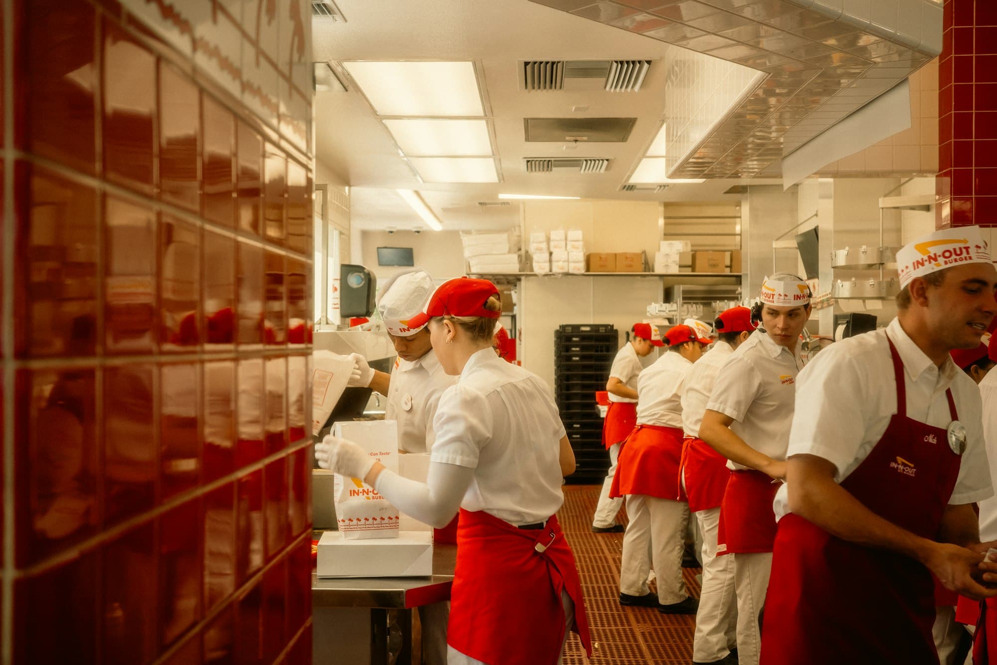 A line of cooks in red aprons working a busy restaurant kitchen.