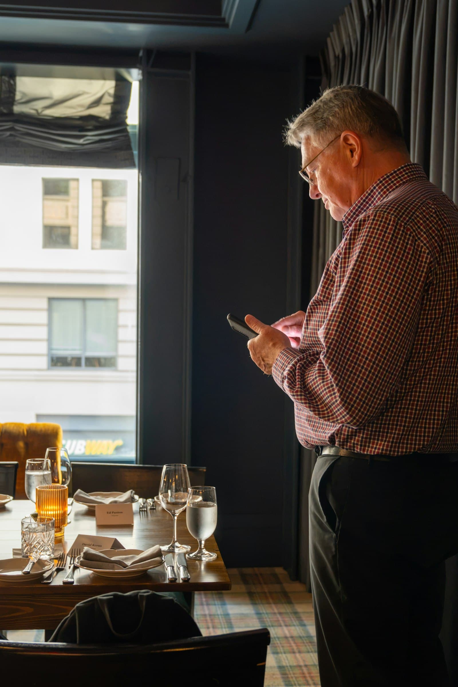 An owner reads his phone in an empty dining room before opening.